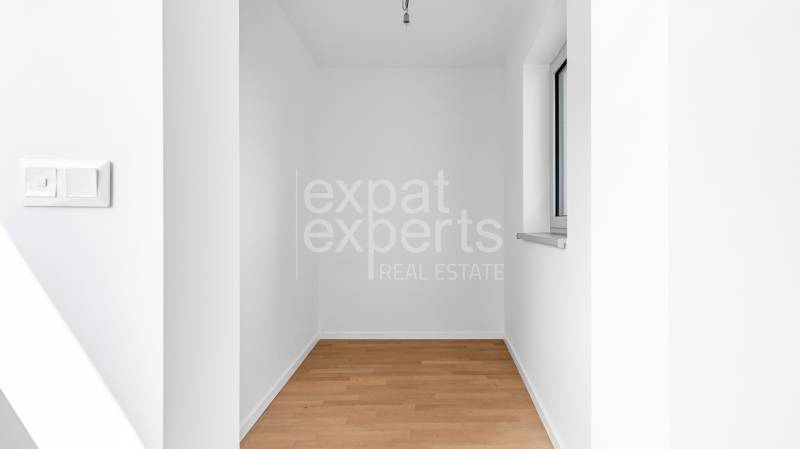 A small room with white walls and a floor with a wooden decor in a 4-room apartment.