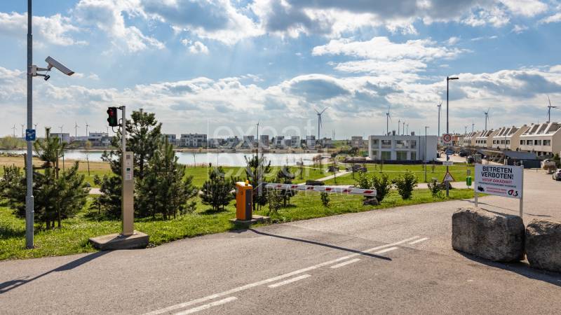 A system of wind turbines and a lake on Am Seepark street in Kittsee behind the barrier.
