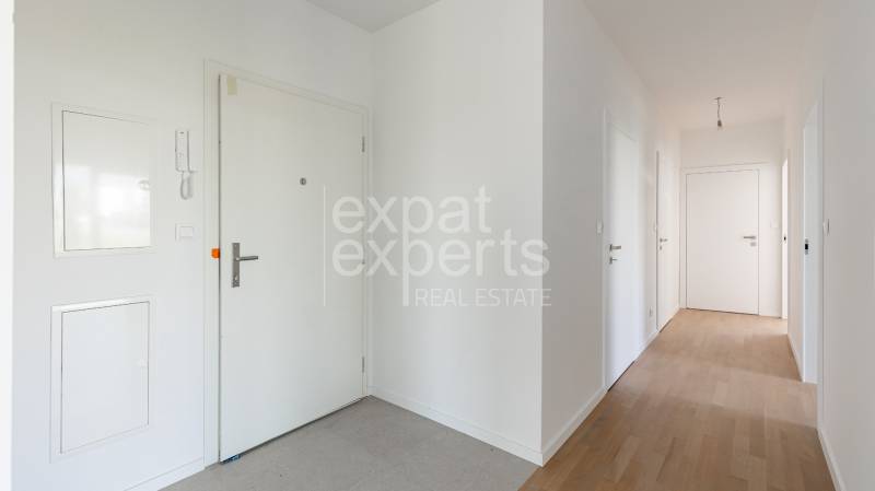 A hallway in a 4-room apartment with a wooden decor floor and white doors.