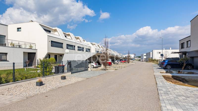 Row houses in Kittsee on Am Seepark Street with parking and a spacious road.