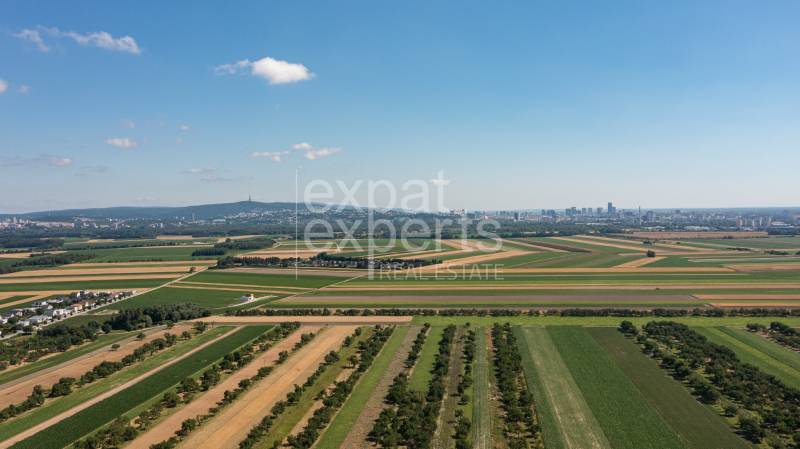 An aerial view of fields and the skyline of Bratislava, with the city in the distance.