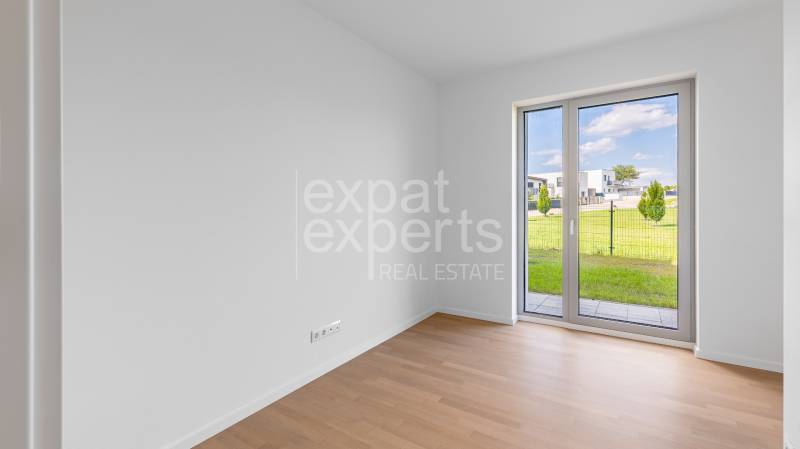 A room with a wooden decor floor in a 4-room apartment with a garden view.