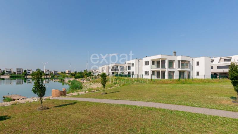 Modern buildings by the lake in Kittsee, at Am Seepark, in a sunny landscape.