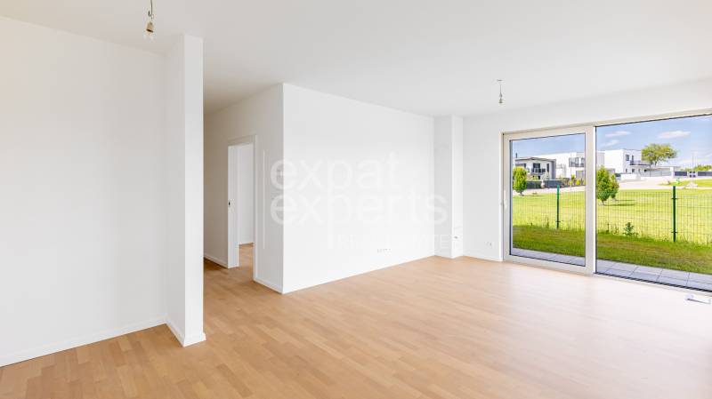 Bright 4-room apartment with wood-patterned flooring and spacious windows on the ground floor.