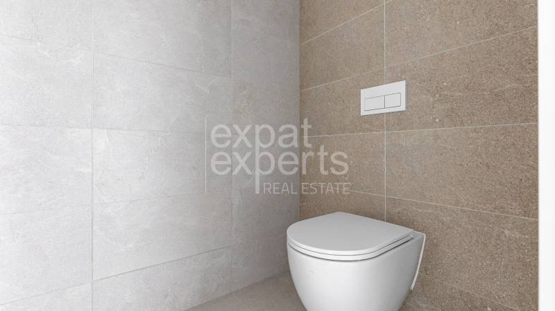 A toilet in the bathroom with light tiles in a 4-room apartment.