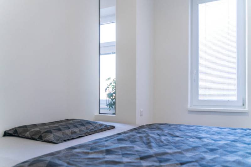 Bright bedroom with a bed and a window with blinds in a 2-room apartment.