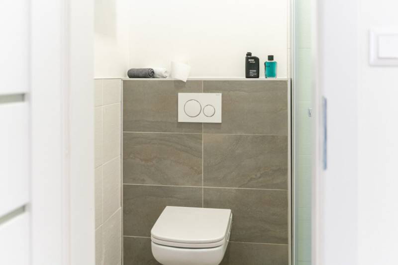 Bathroom with toilet in a 2-room apartment with ceramic tiles and accessories.