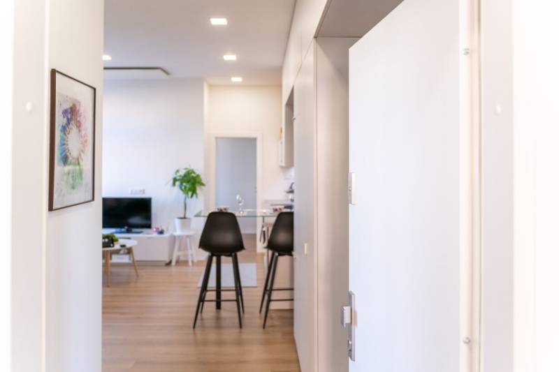 Interior of a 2-room apartment with a wooden decor floor, paintings, and a kitchen area.