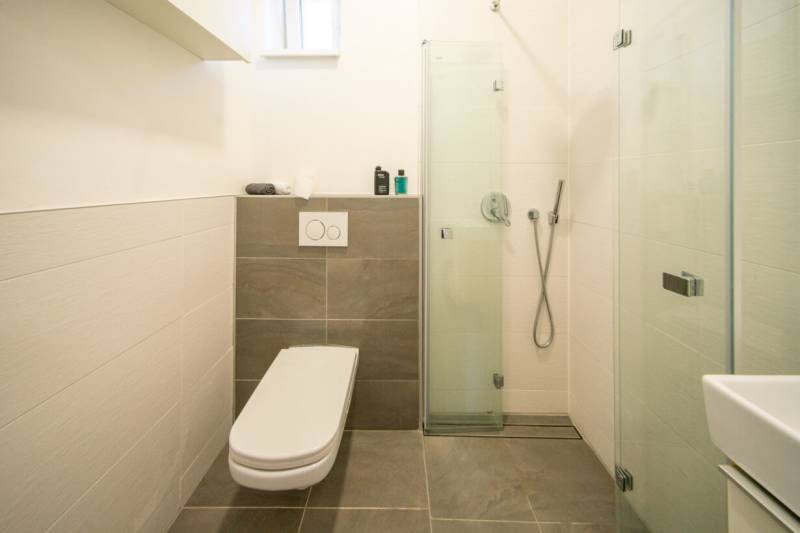 Bathroom with a shower and toilet in a 2-room apartment.