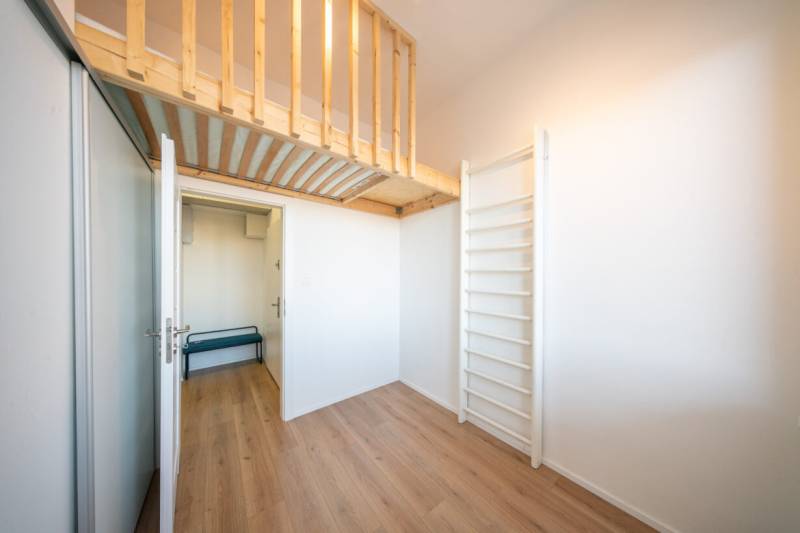 A room in a 2-room apartment with a climbing frame, a raised loft, and a floor with a wooden decor.