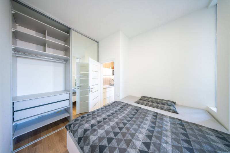 Bedroom in a 2-room apartment with a bed, wardrobe, and floor with a wooden decor.