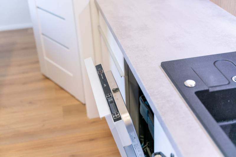 A kitchen with a dishwasher and a wooden decor floor in a 2-room apartment.