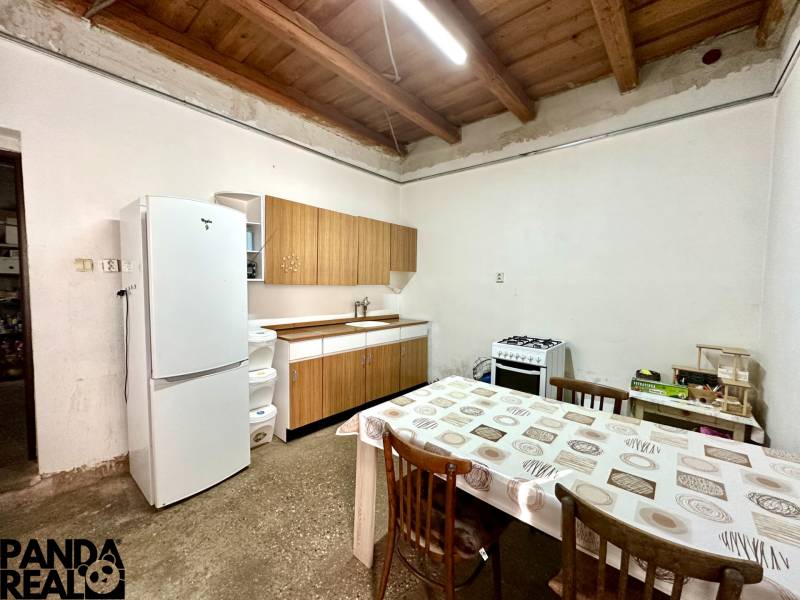 Dining table and kitchen with a white refrigerator and stove in a family house.
