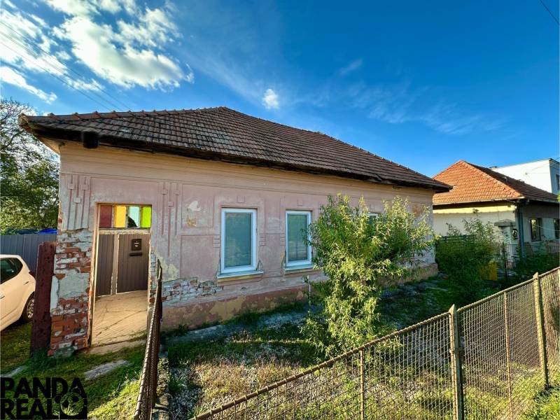 A family house in Ludanice with fencing and a simple facade, with a blue sky in the background.