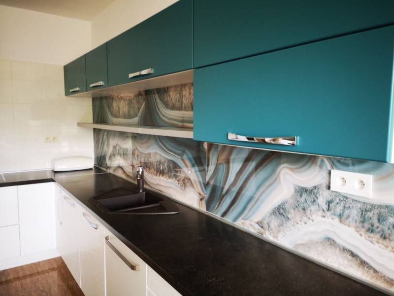 A kitchen in a 3-room apartment with a striking wall and a wooden decor floor.