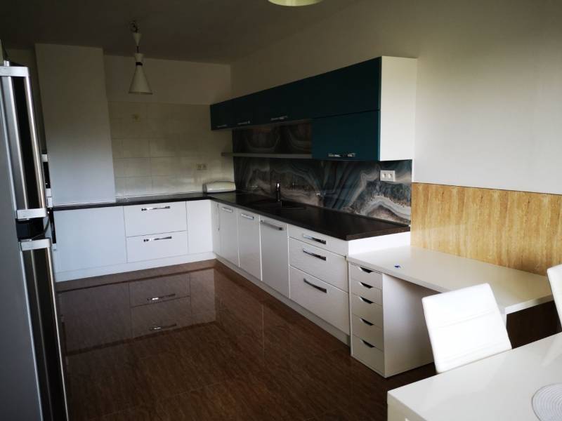 A kitchen in a 3-room apartment with a glossy floor and modern cabinets.