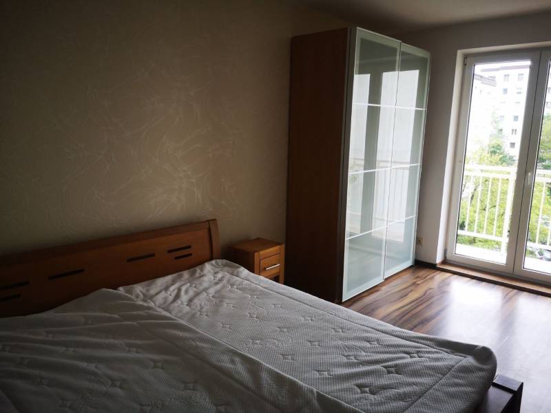 A bedroom in a 3-room apartment with a bed, wardrobe, and floor with a wooden decor.