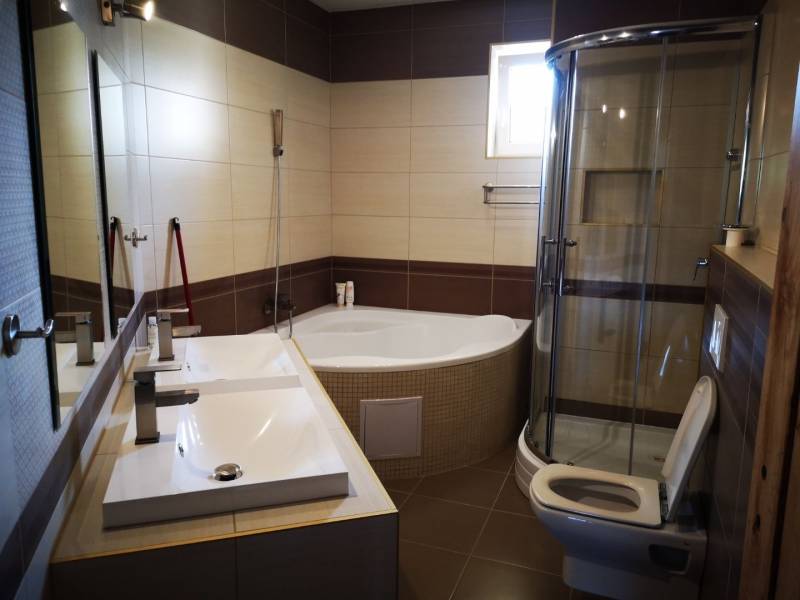 A bathroom with a bathtub, shower, and sink in a 3-room apartment, elegant design.