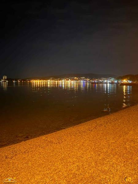Night beach in the town of Vodice, Croatia, with the reflection of city lights on the water.