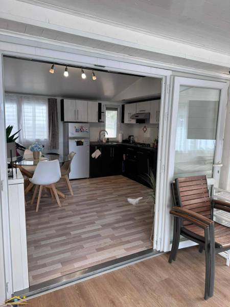 An interior with a light table, chairs, kitchen unit, and a floor with a wooden decor.