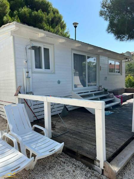 A white wooden house with loungers on a pebble terrace in the town of Vodice, Croatia.