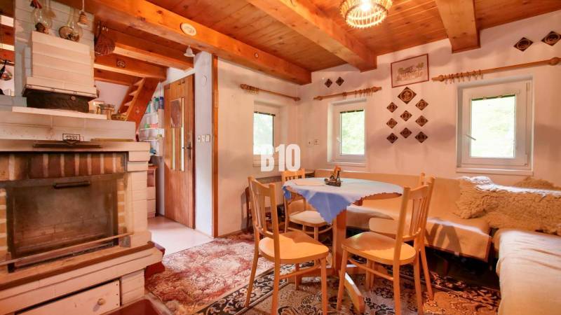 The interior of a cottage with a tiled stove, wooden furniture, and decorations on the walls.