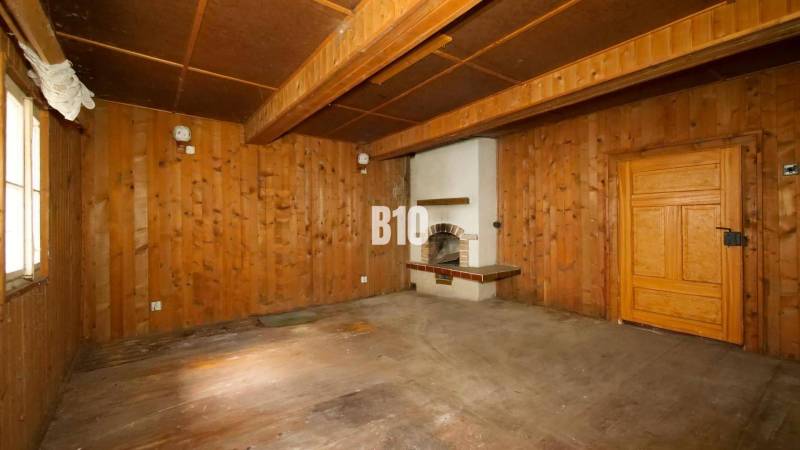 Interior of a cabin with wooden walls, floor, and fireplace.