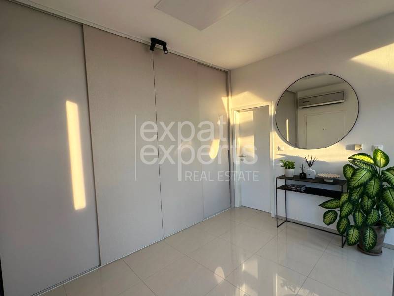 Interior of a 3-room apartment with a large round mirror, a plant, and a built-in wardrobe.
