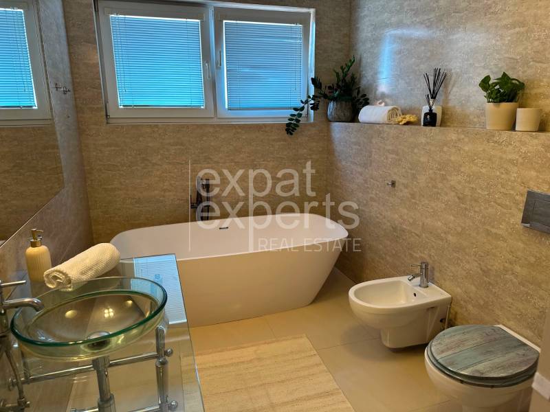 A bathroom in a 3-room apartment with a separate bathtub and decorative plants.