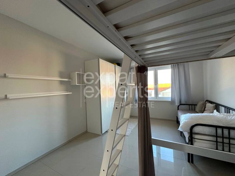 A room with a bunk bed, a bed, white curtains, and storage space in a 3-room apartment.