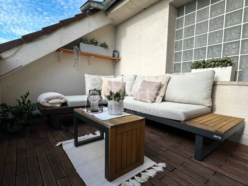 Outdoor terrace of a 3-room apartment with comfortable seating, plants, and flooring with a wooden decor.
