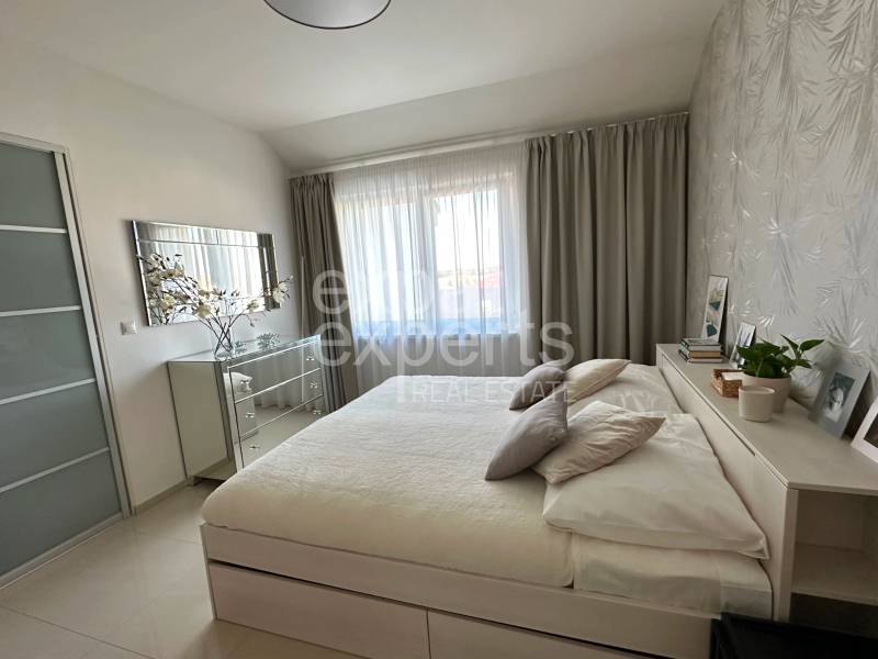 A bright bedroom with a large bed and a mirrored dresser in a 3-room apartment.