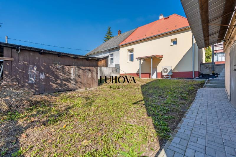 The garden of a family house in Lednické Rovne on Sklárska street shows a wooden extension and a walkway.