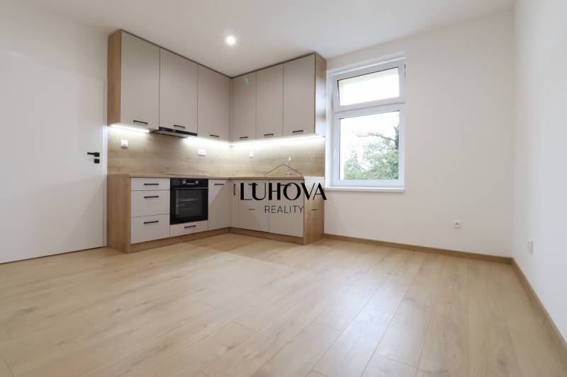 A kitchen in a family house with a wooden decor floor, built-in appliances, white walls.