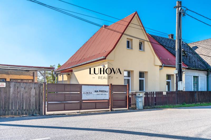 A family house on Sklárska Street in Lednické Rovne with a red roof and a wooden fence.