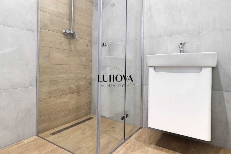 A bathroom in a family house with a wooden decor floor and a shower corner.
