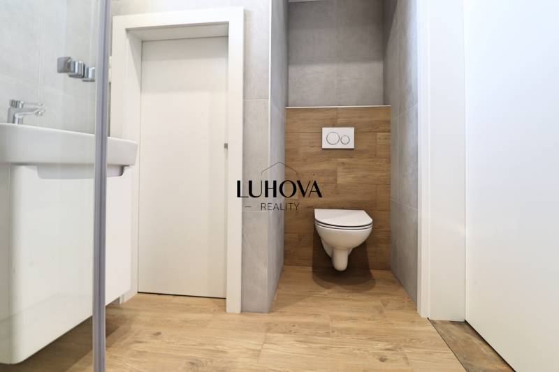 A bathroom in a family house with a toilet and a wooden decor floor.