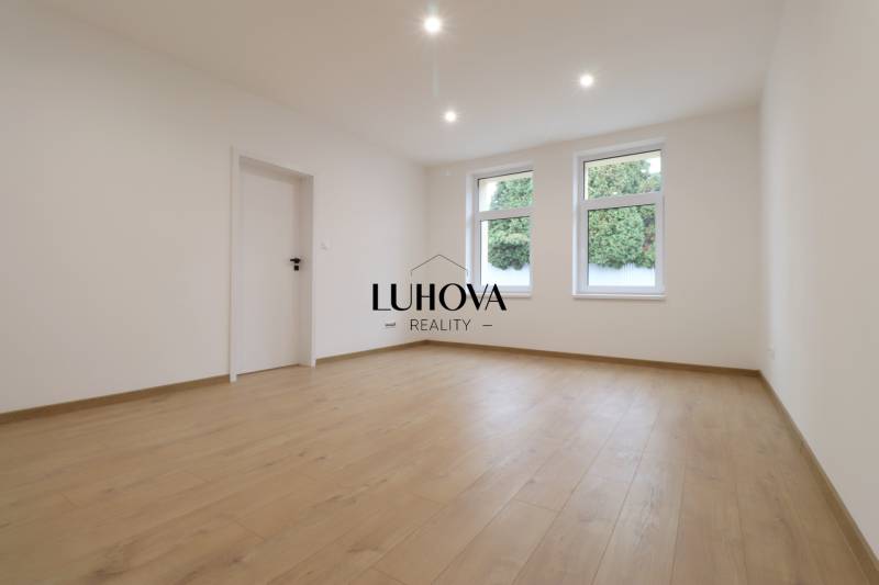A spacious room with a wooden decor floor and white walls in a family house.