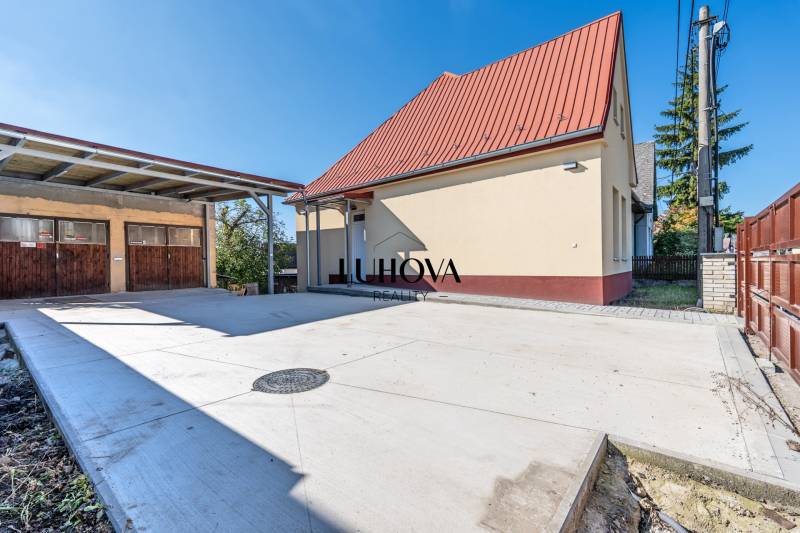 A family house on Sklárska Street in Lednické Rovne with adjacent buildings and a paved area.