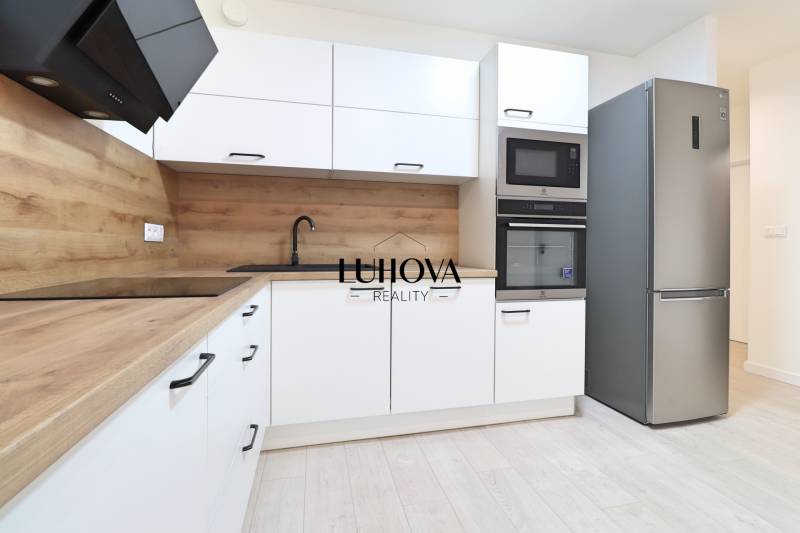 A kitchen in a 4-room apartment with modern appliances, wood-patterned flooring, and light-colored cabinets.