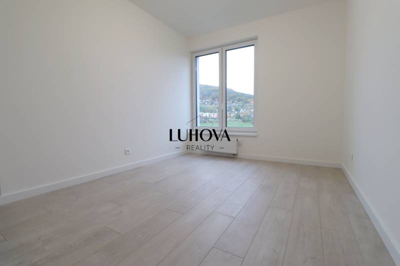 A room in a 4-room apartment with a wooden decor floor and a large window.