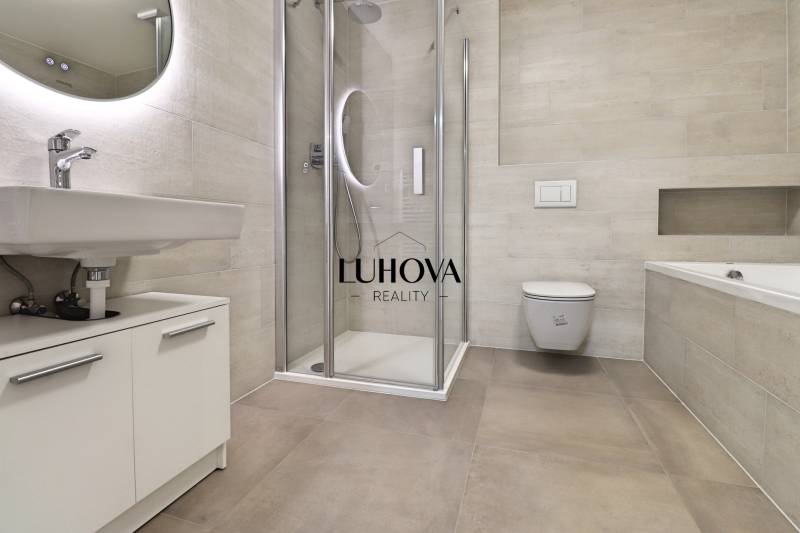 Bathroom in a 4-room apartment with a toilet, shower, and bathtub, complemented by a mirror.