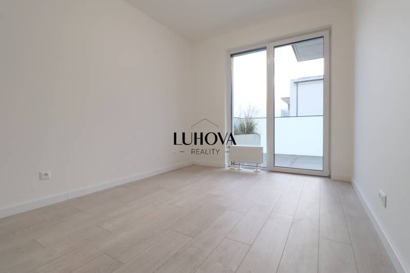 A bright room in a 4-room apartment with a wood-patterned floor and a large window.