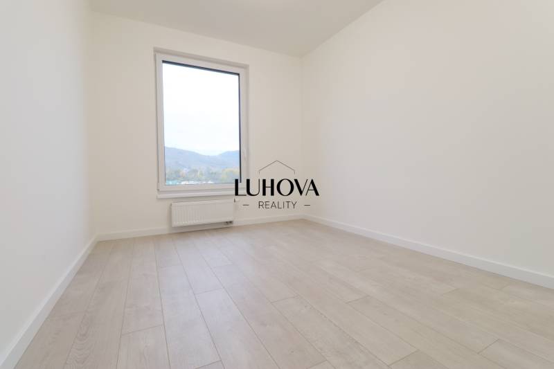 A bright room with a wall and a large window, wooden decor flooring in a 4-room apartment.