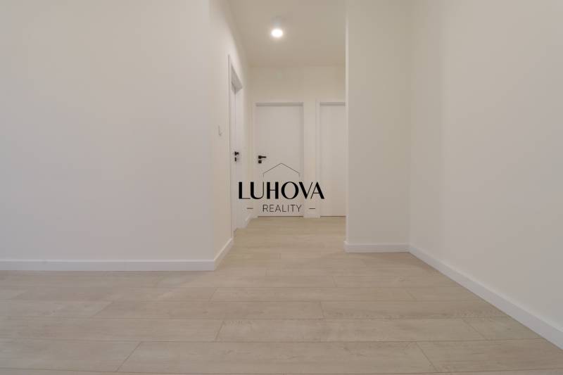A hallway in a 4-room apartment with white walls and a floor with a wooden decor.