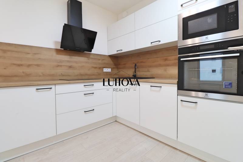 White kitchen with wood-patterned flooring and modern appliances in a 4-room apartment.
