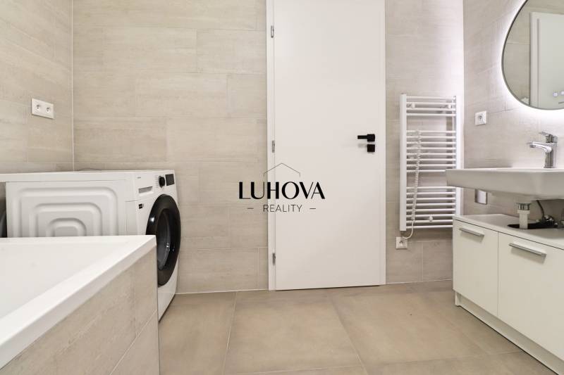 A bathroom with a shower, washing machine, and sink in a 4-room apartment.