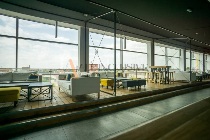 Gastro premises with large windows, wooden decor flooring, and comfortable seating.