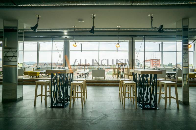 Interior of gastro spaces with high tables and large windows, floor with wood decor.