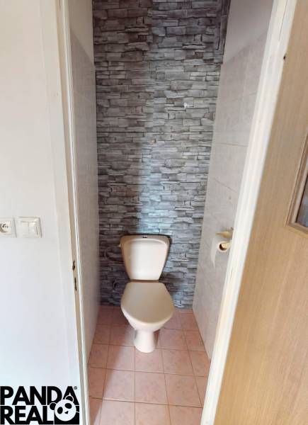 A toilet with stone-like tiles in a 4-room apartment.